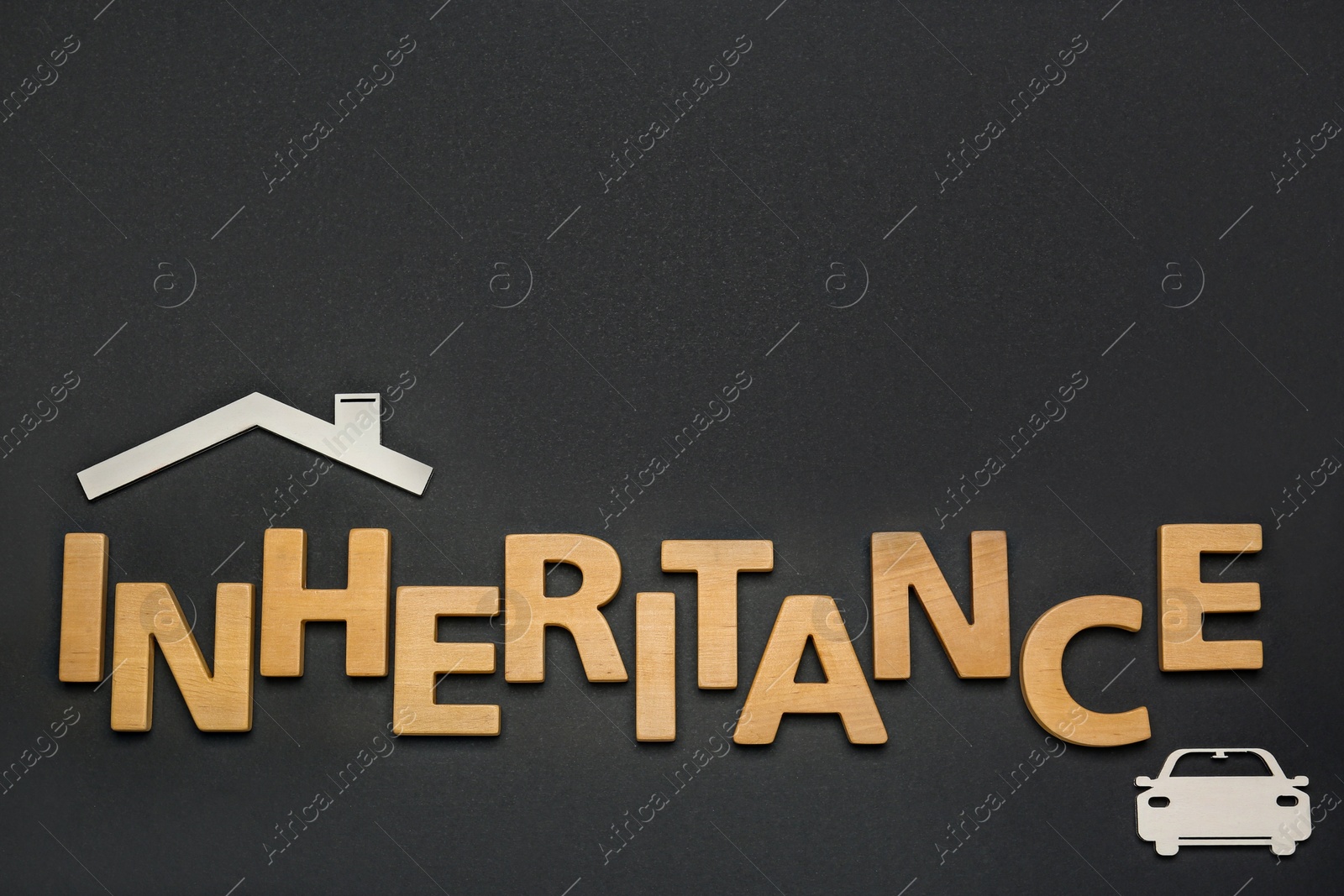 Photo of Word Inheritance made with wooden letters and different cutouts on black background, flat lay. Space for text