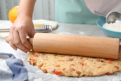 Photo of Woman rolling dough for Stollen at grey table, closeup. Baking traditional German Christmas bread