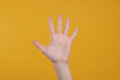 Photo of Woman giving high five on orange background, closeup
