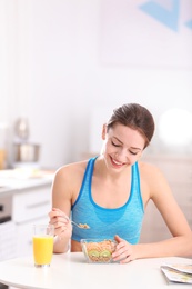Photo of Young woman in fitness clothes having healthy breakfast at home