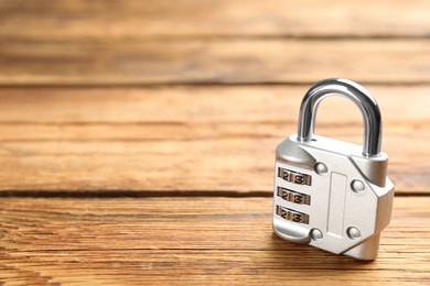 Photo of Modern combination lock on wooden table. Space for text