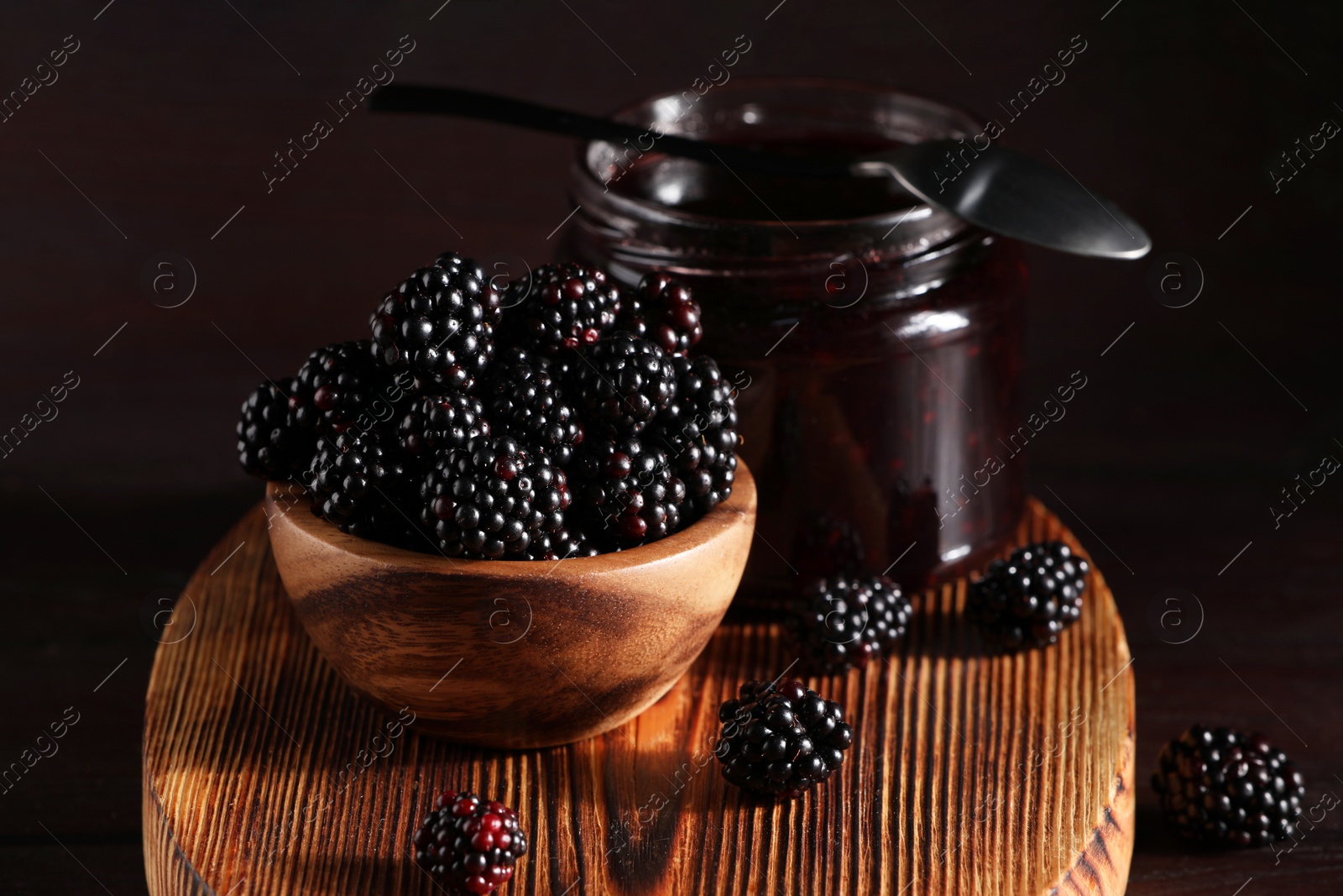 Photo of Fresh ripe blackberries and tasty jam on wooden board