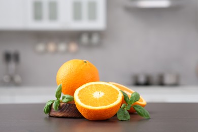 Photo of Whole and cut oranges on wooden counter in kitchen