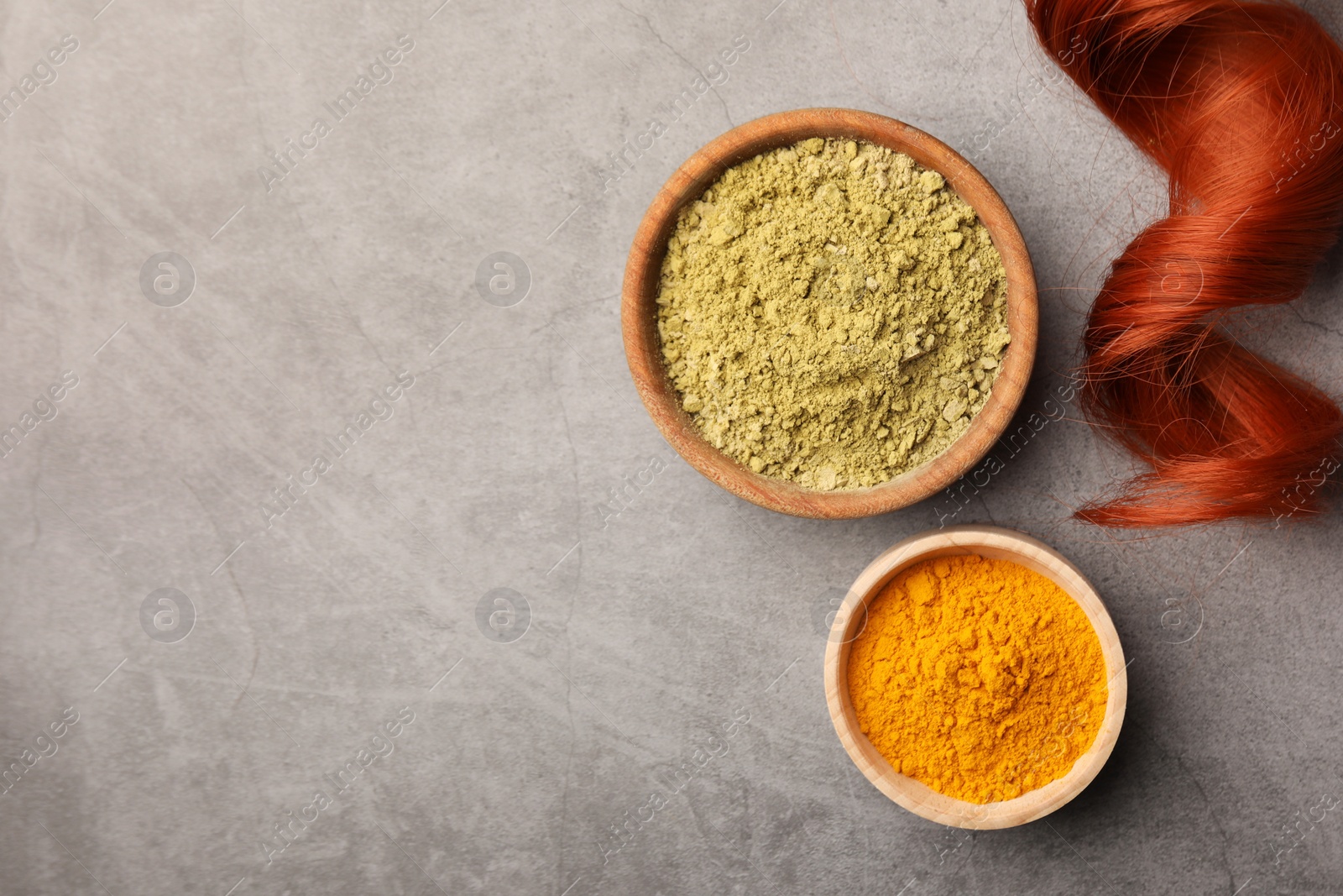 Photo of Red strand, henna and turmeric powder on grey table, flat lay with space for text. Natural hair coloring