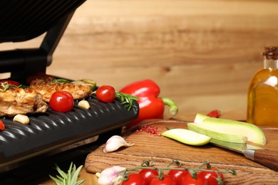 Photo of Electric grill with different products and knife on table