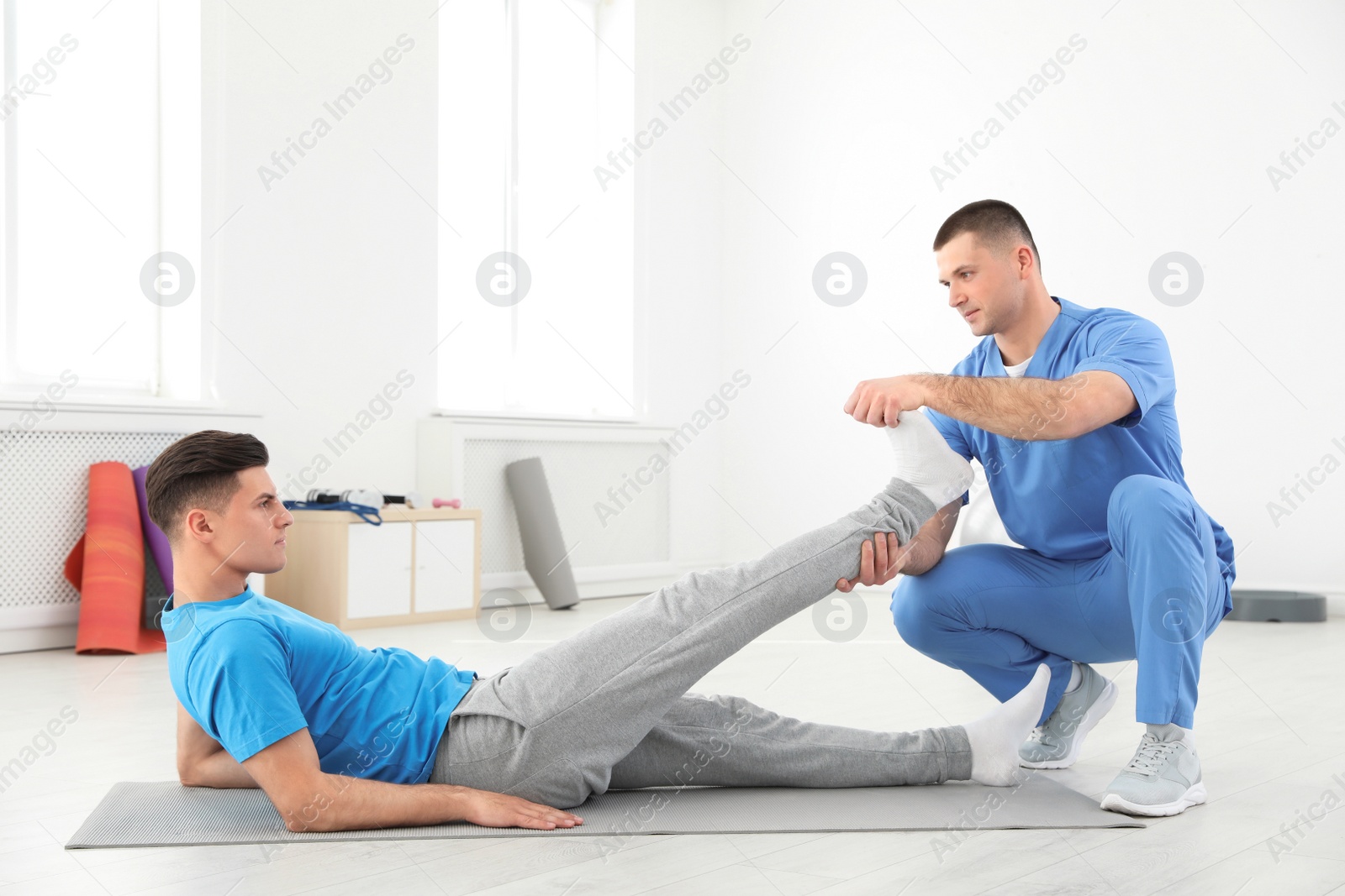 Photo of Professional physiotherapist working with male patient in rehabilitation center