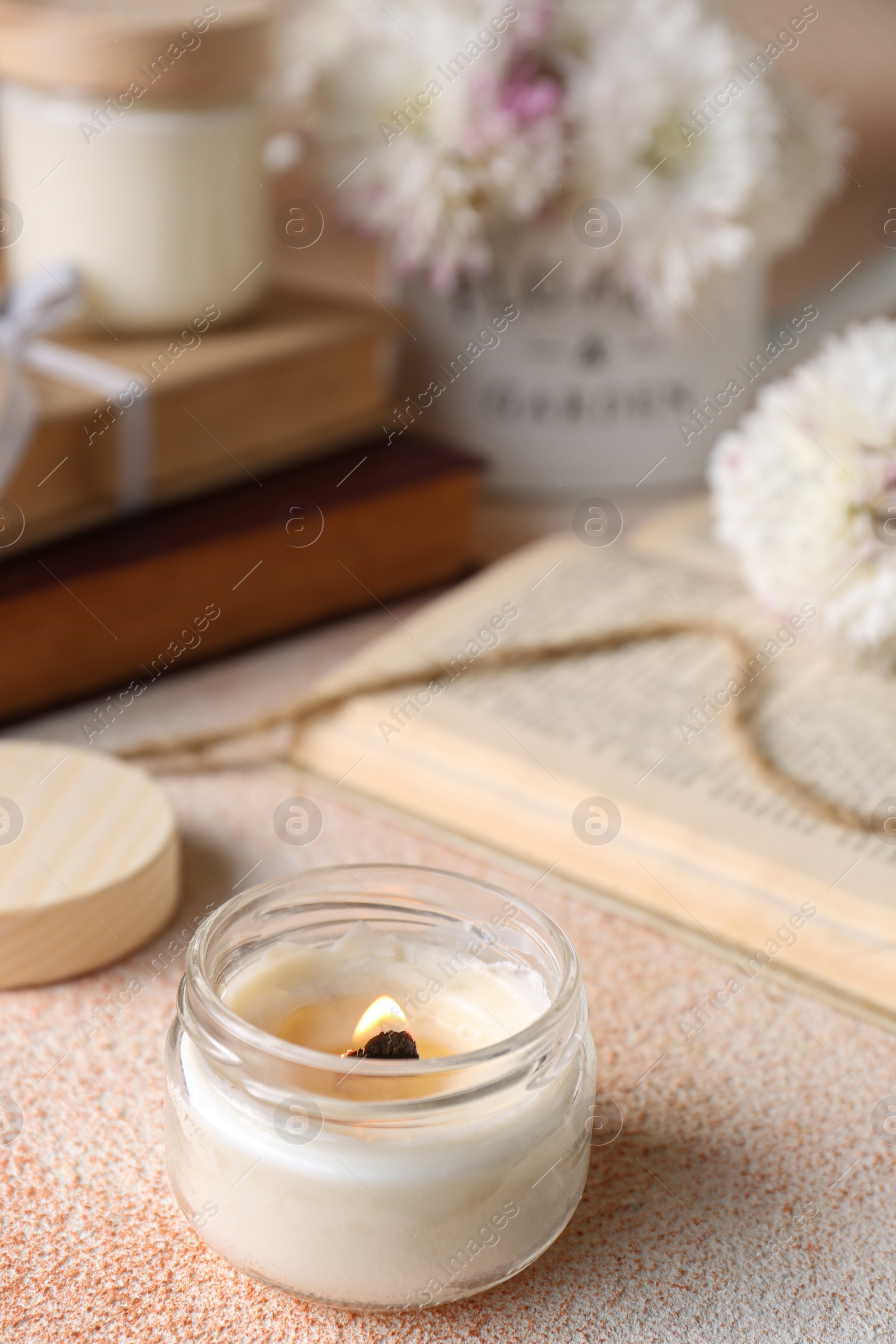 Photo of Burning candle on beige textured table, closeup