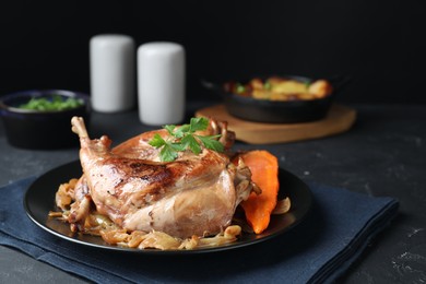 Photo of Tasty cooked rabbit meat with vegetables served on black table, closeup. Space for text