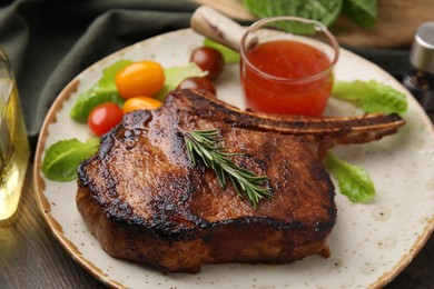 Tasty grilled meat, rosemary, tomatoes and marinade on wooden table, closeup