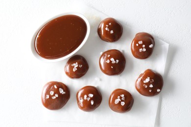 Photo of Tasty candies, caramel sauce and salt on white table, top view