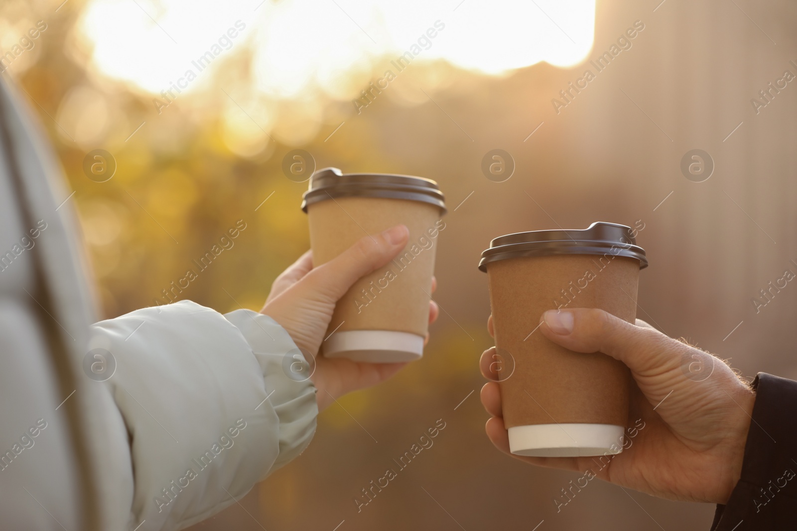 Photo of Couple with takeaway coffee cups outdoors, closeup