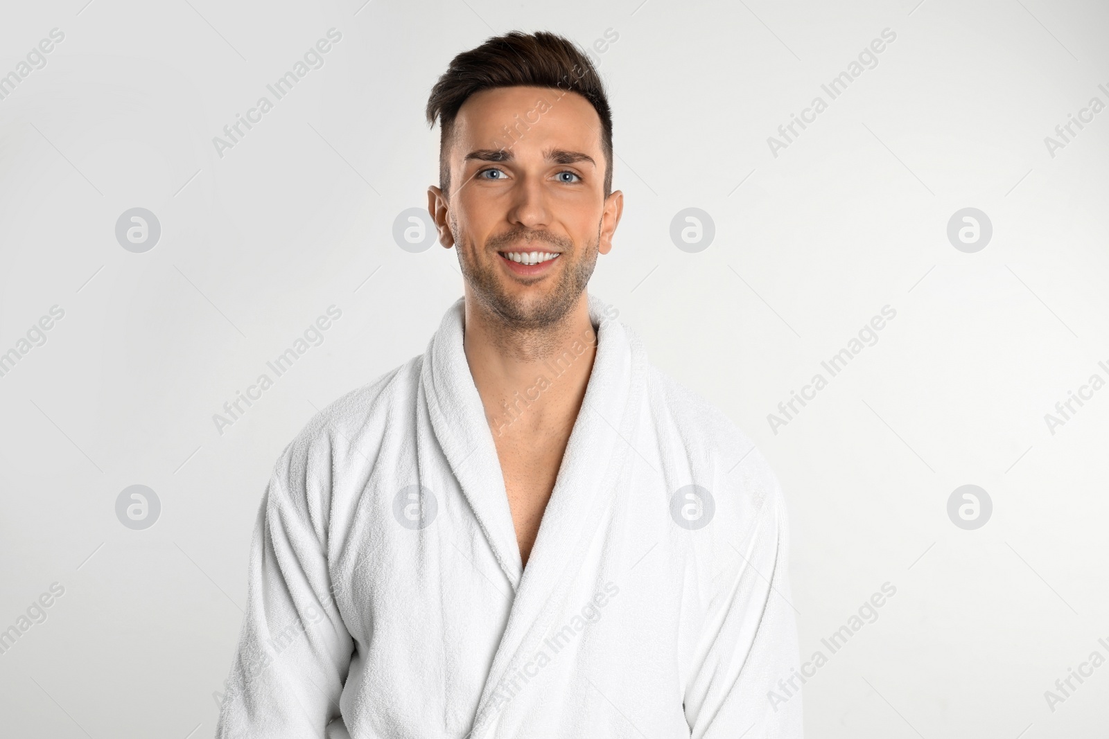 Photo of Happy young man in bathrobe on white background