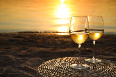 Photo of Glasses of delicious wine on riverside at sunset