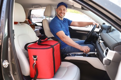 Male courier with thermo bag in car. Food delivery service