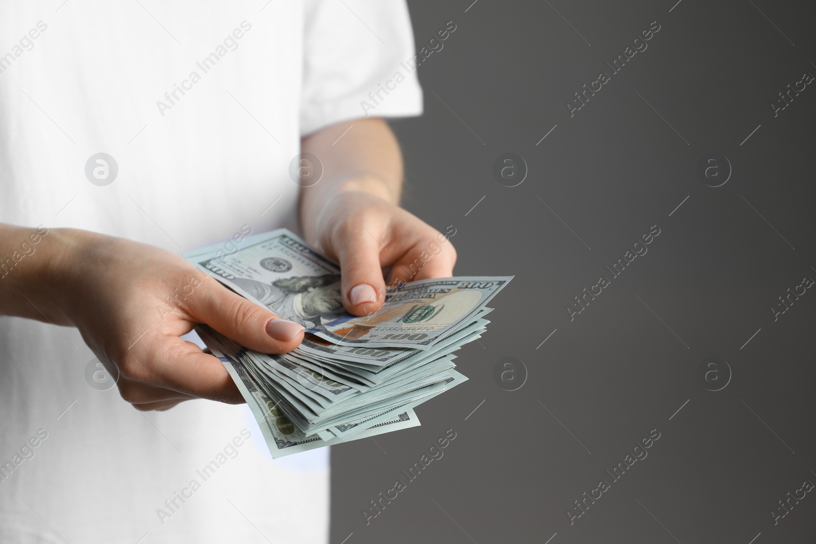 Photo of Money exchange. Woman counting dollar banknotes on grey background, closeup. Space for text