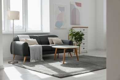 Stylish living room with gray couch, white coffee table and lamp. Interior design