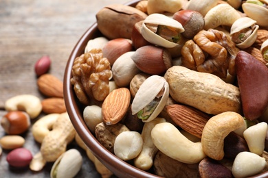 Photo of Bowl with mixed organic nuts on table, closeup