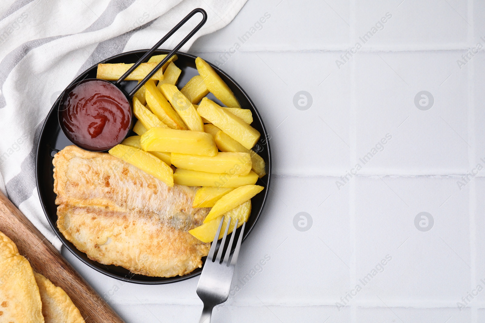 Photo of Delicious fish and chips served on white tiled table, flat lay. Space for text