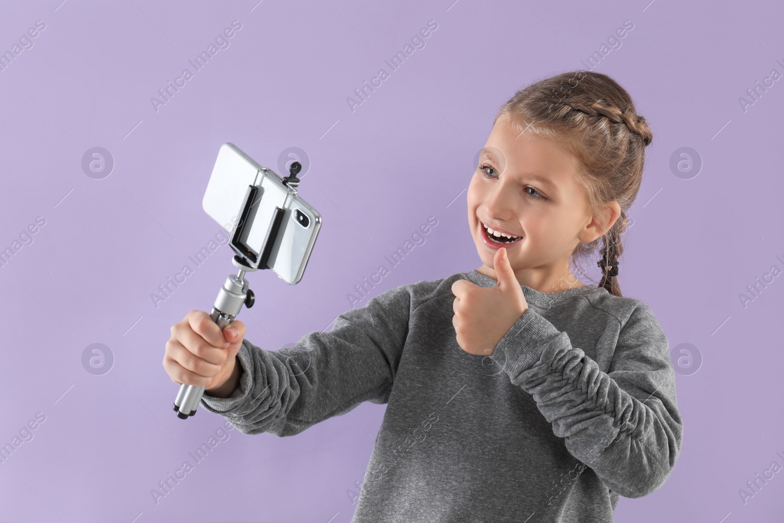 Photo of Cute little blogger recording video on violet background