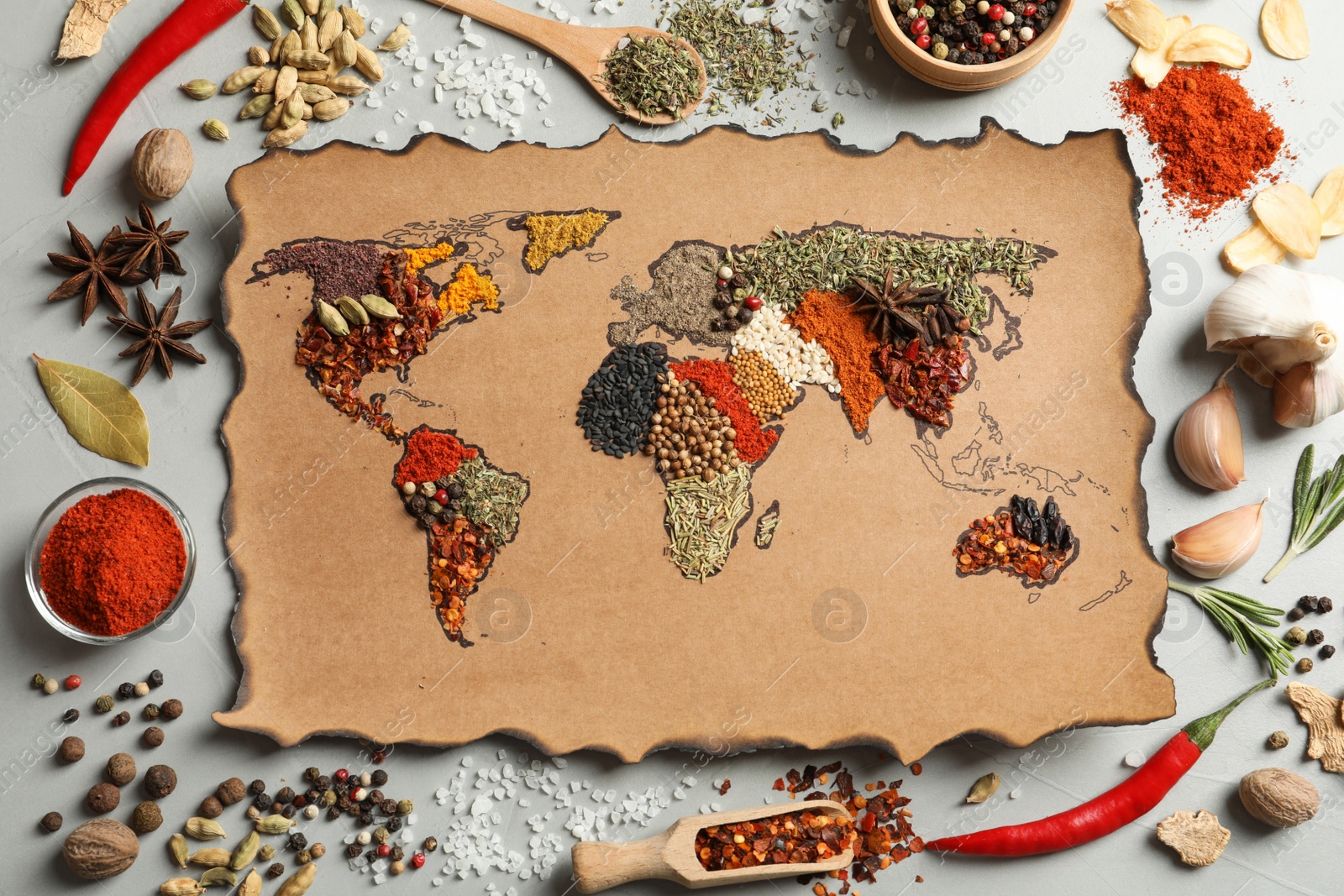 Photo of Paper with world map made of different aromatic spices on gray background, flat lay