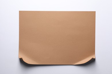 Photo of Empty kraft paper sheet with curved borders isolated on white, top view