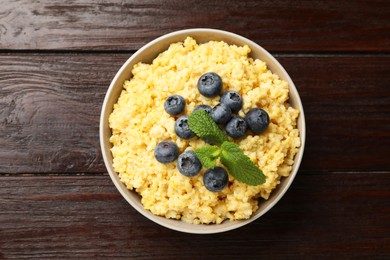 Photo of Tasty millet porridge with blueberries and mint in bowl on wooden table, top view