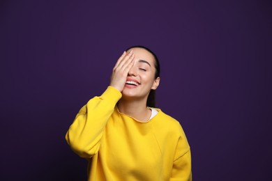 Beautiful young woman laughing on purple background. Funny joke