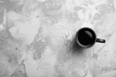 Ceramic cup with hot aromatic coffee on grunge background, top view