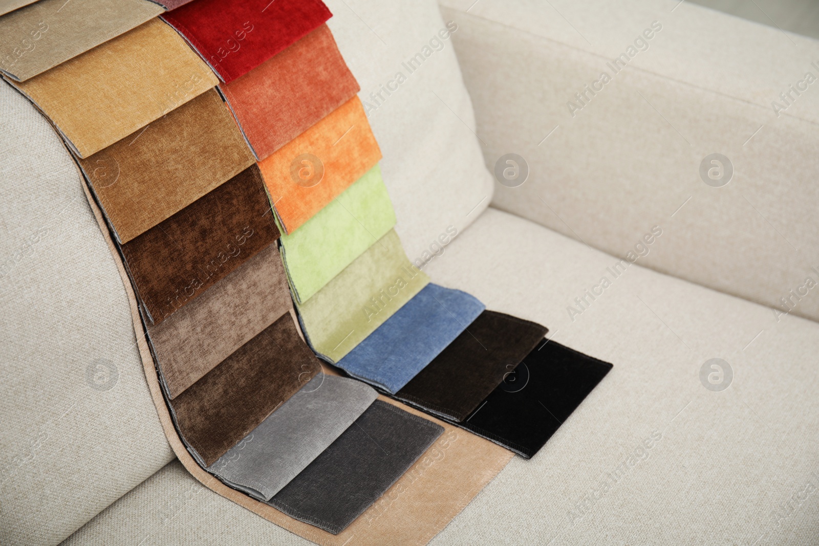 Photo of Catalog of colorful fabric samples on beige sofa