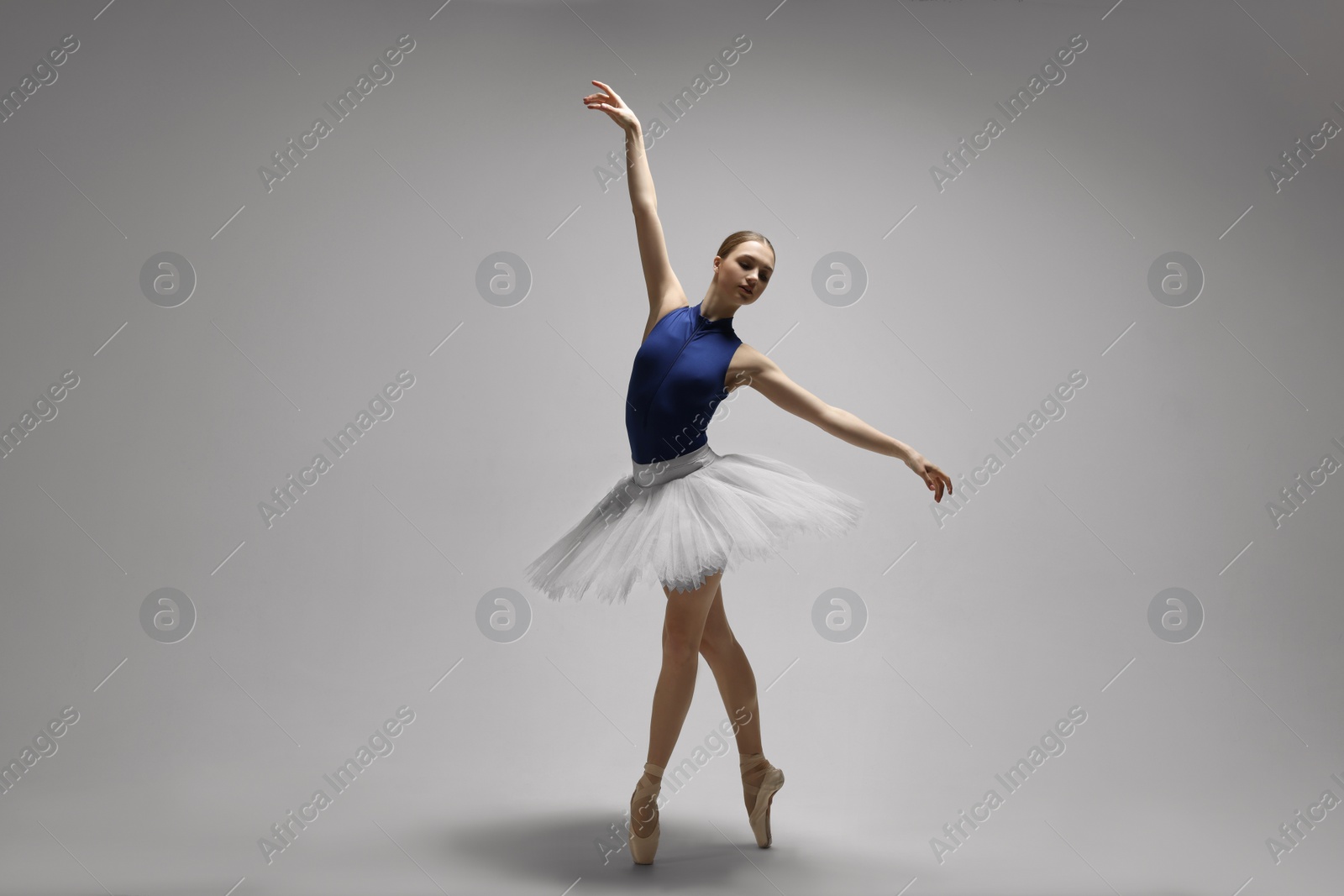 Photo of Young ballerina practicing dance moves on grey background. Space for text