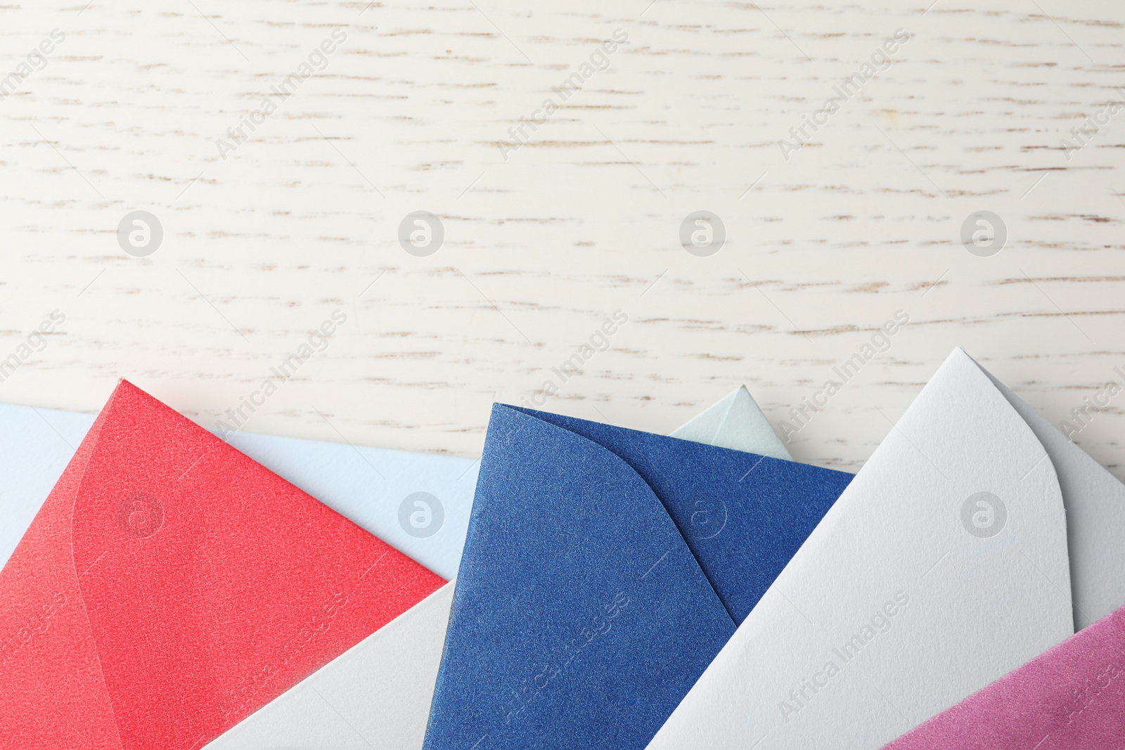 Photo of Colorful paper envelopes on white wooden background, flat lay. Space for text