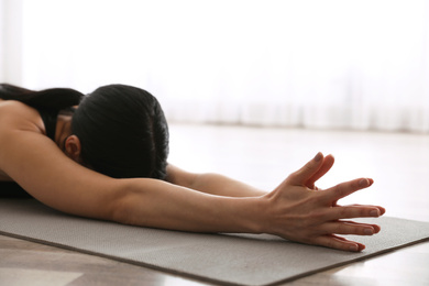 Photo of Young woman practicing extended child's asana in yoga studio, closeup. Utthita Balasana pose