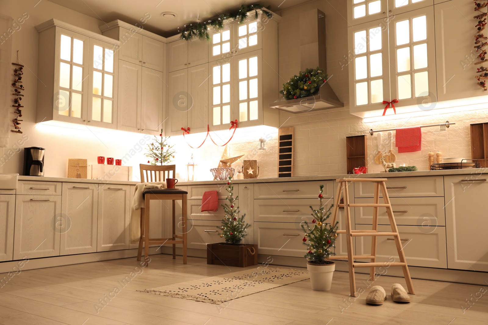 Photo of Small Christmas trees and festive decor in kitchen