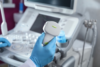 Sonographer holding ultrasound machine probe in clinic, closeup