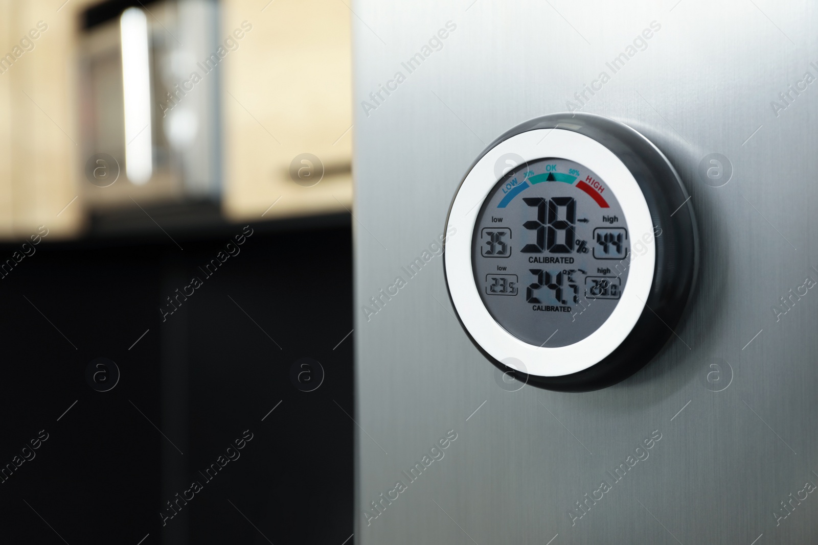 Photo of Round digital hygrometer with thermometer on fridge in kitchen. Space for text