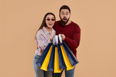 Photo of Excited couple with shopping bags on beige background