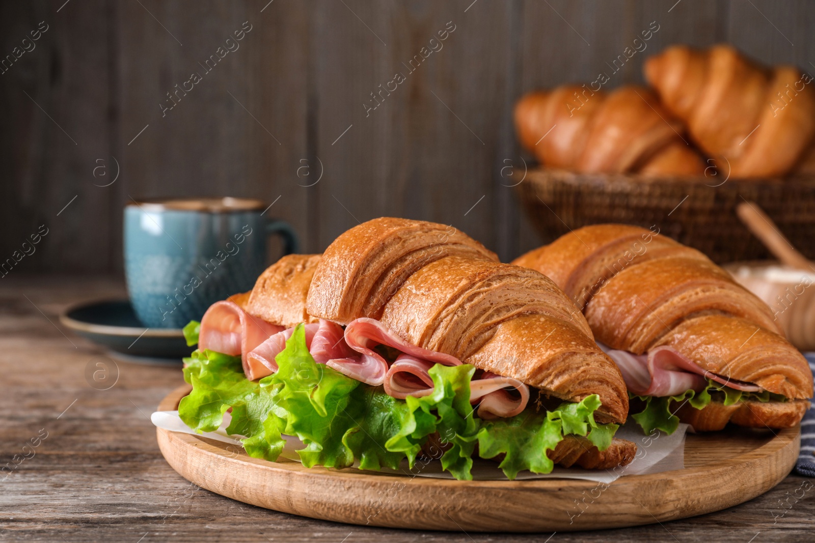 Photo of Tasty croissant sandwiches with ham on wooden table, closeup