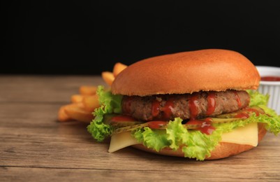 Tasty burger with patty, lettuce and cheese on wooden table, closeup. Space for text