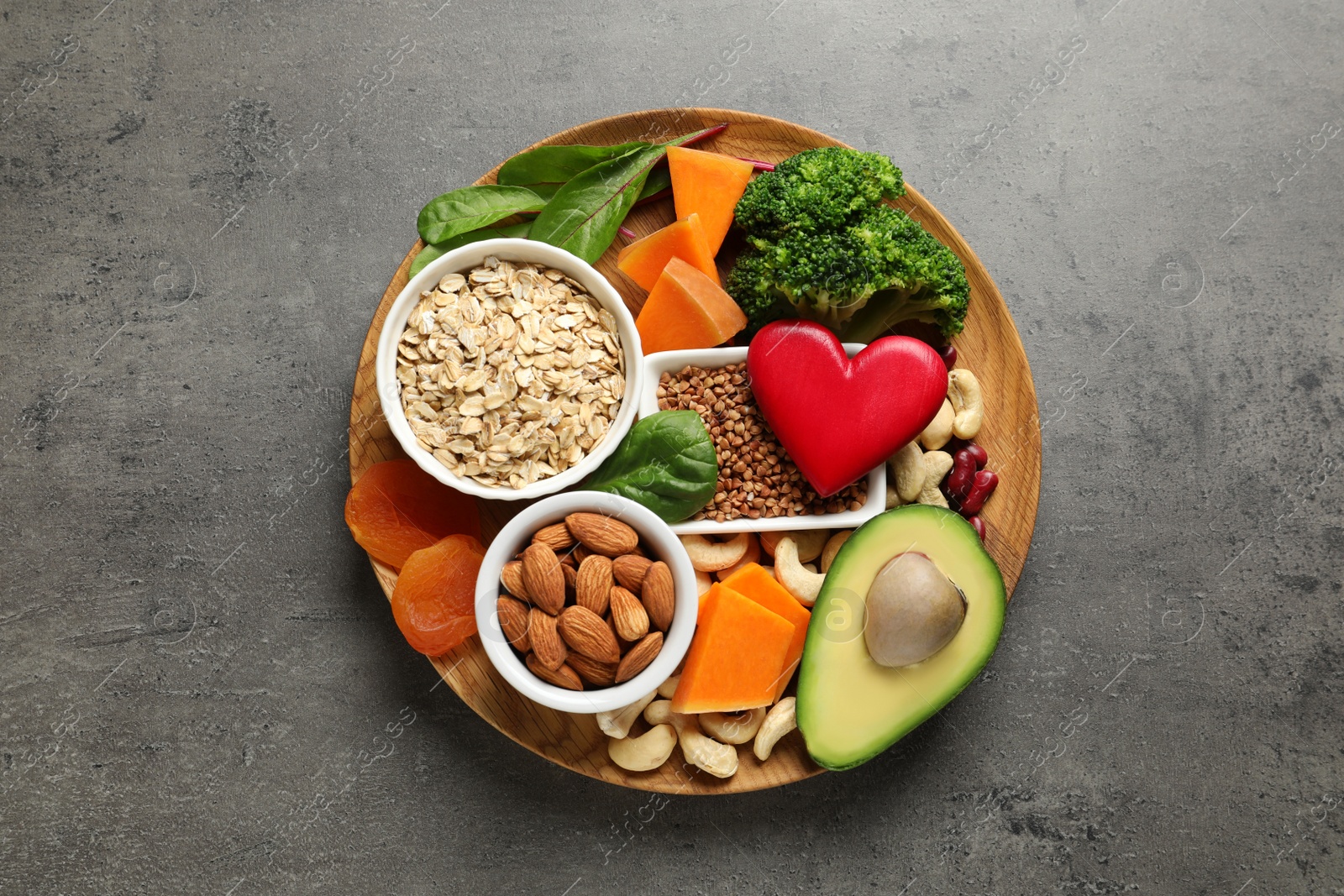 Photo of Wooden plate with heart-healthy products on grey background, top view