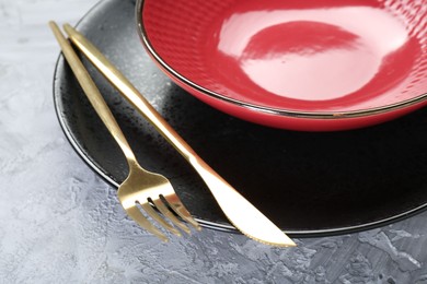Photo of Clean plates, bowl and cutlery on gray textured table, closeup