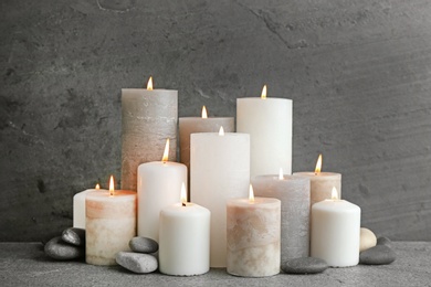 Composition with burning candles on table against grey background