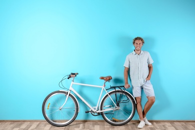 Photo of Handsome man with bicycle against color wall. Space for text