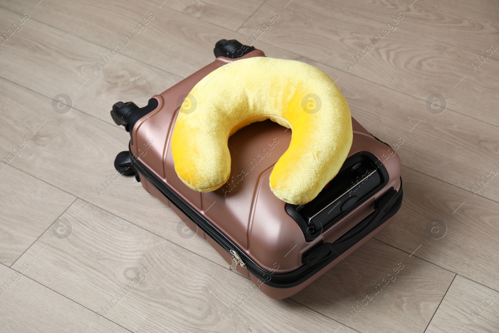 Photo of Yellow travel pillow and suitcase on floor