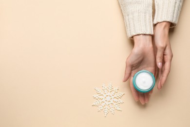 Woman with jar of hand cream on beige background, top view. Space for text