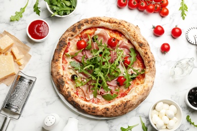 Photo of Tasty pizza with meat and arugula on white marble table, flat lay