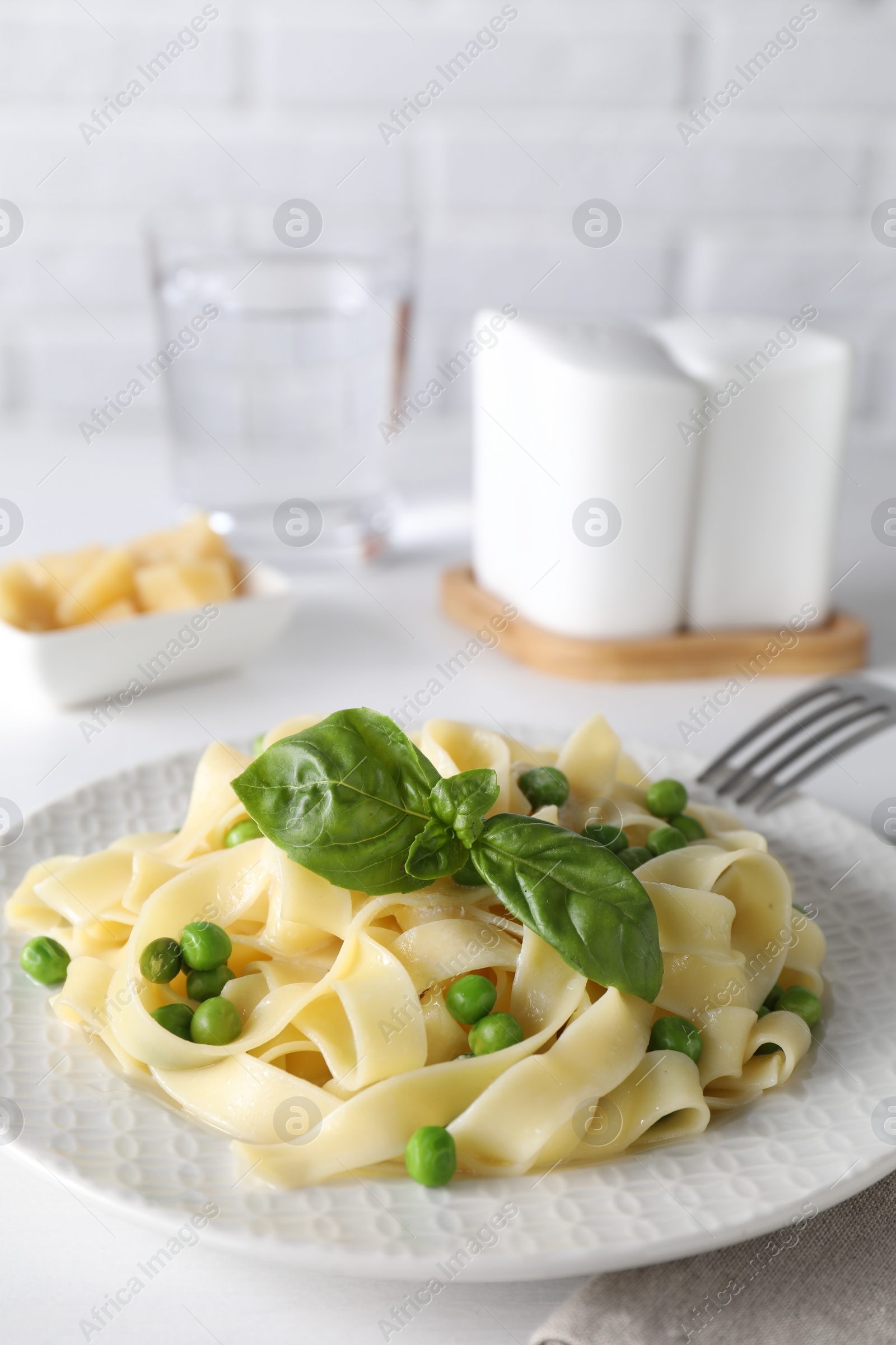 Photo of Delicious pasta with green peas served on white table