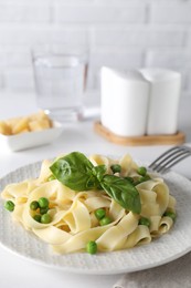 Photo of Delicious pasta with green peas served on white table