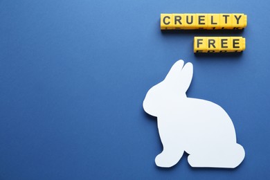 Flat lay of cubes with phrase Cruelty Free and rabbit figure on blue background, space for text. Stop animal tests