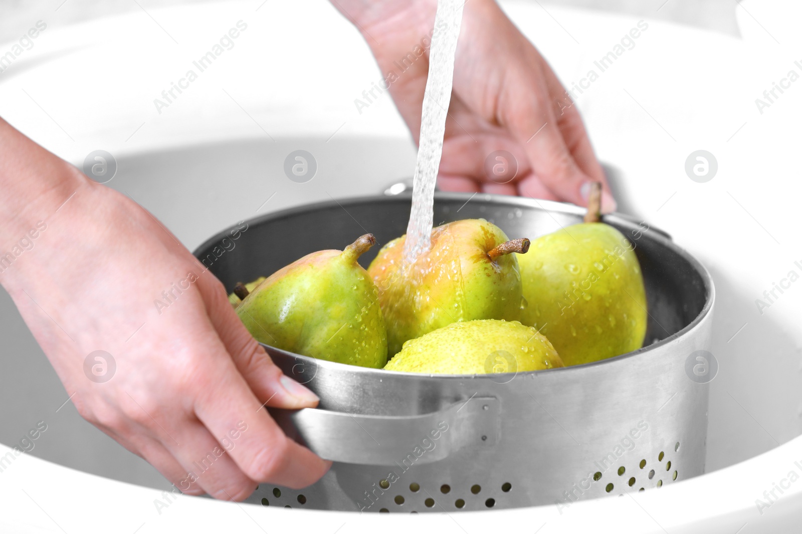 Photo of Woman washing fresh ripe pears in kitchen sink, closeup