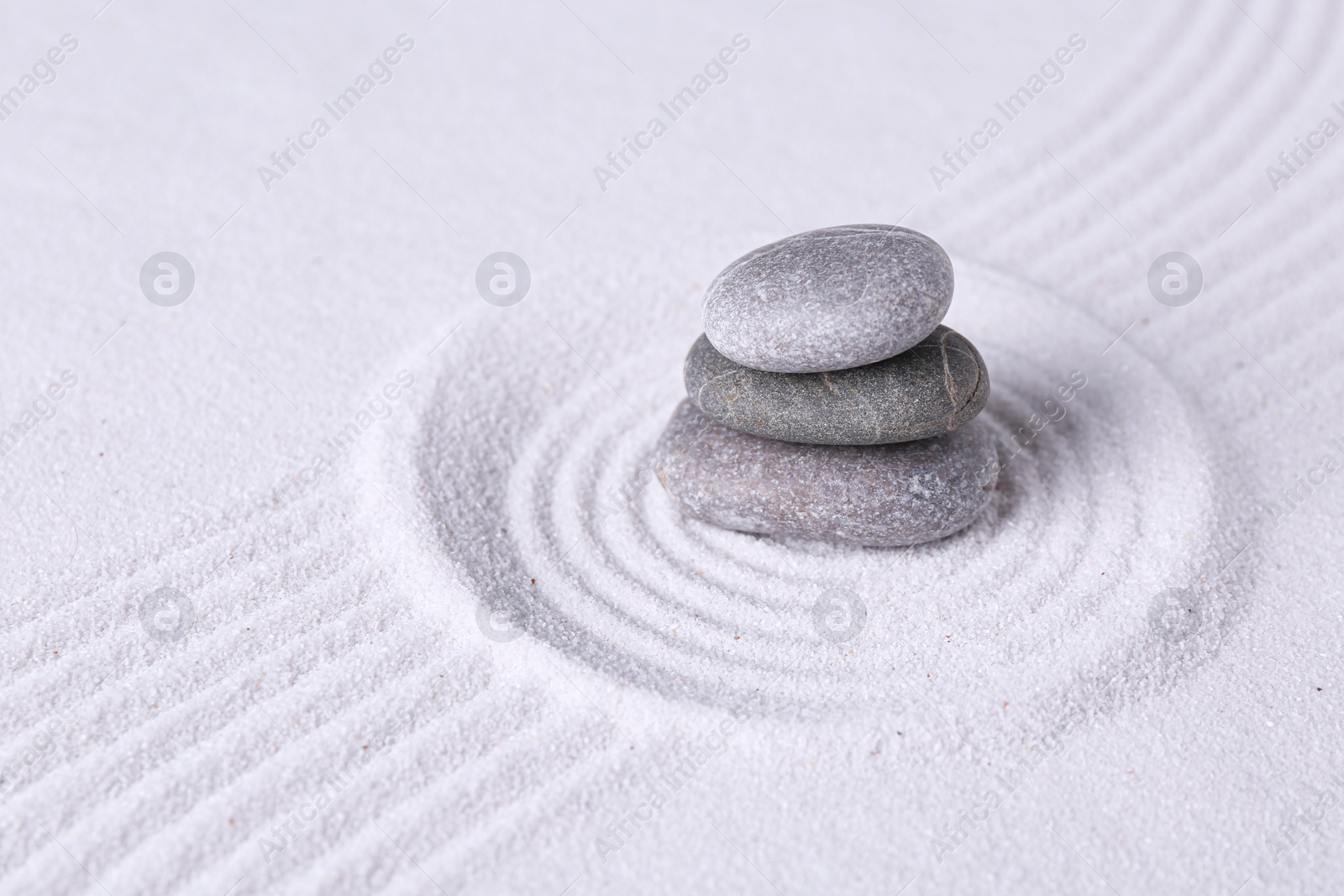 Photo of Zen garden stones on white sand with pattern, space for text